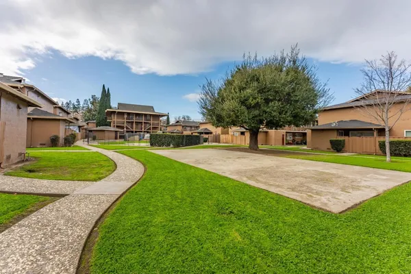 a view of a house with a yard and large trees