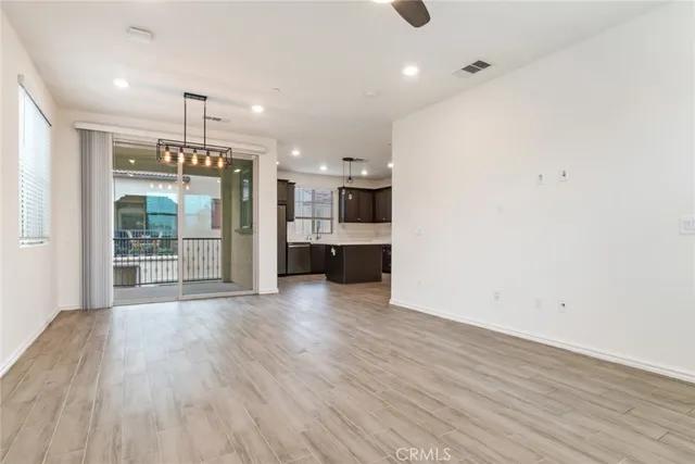 an empty room with wooden floor and a kitchen
