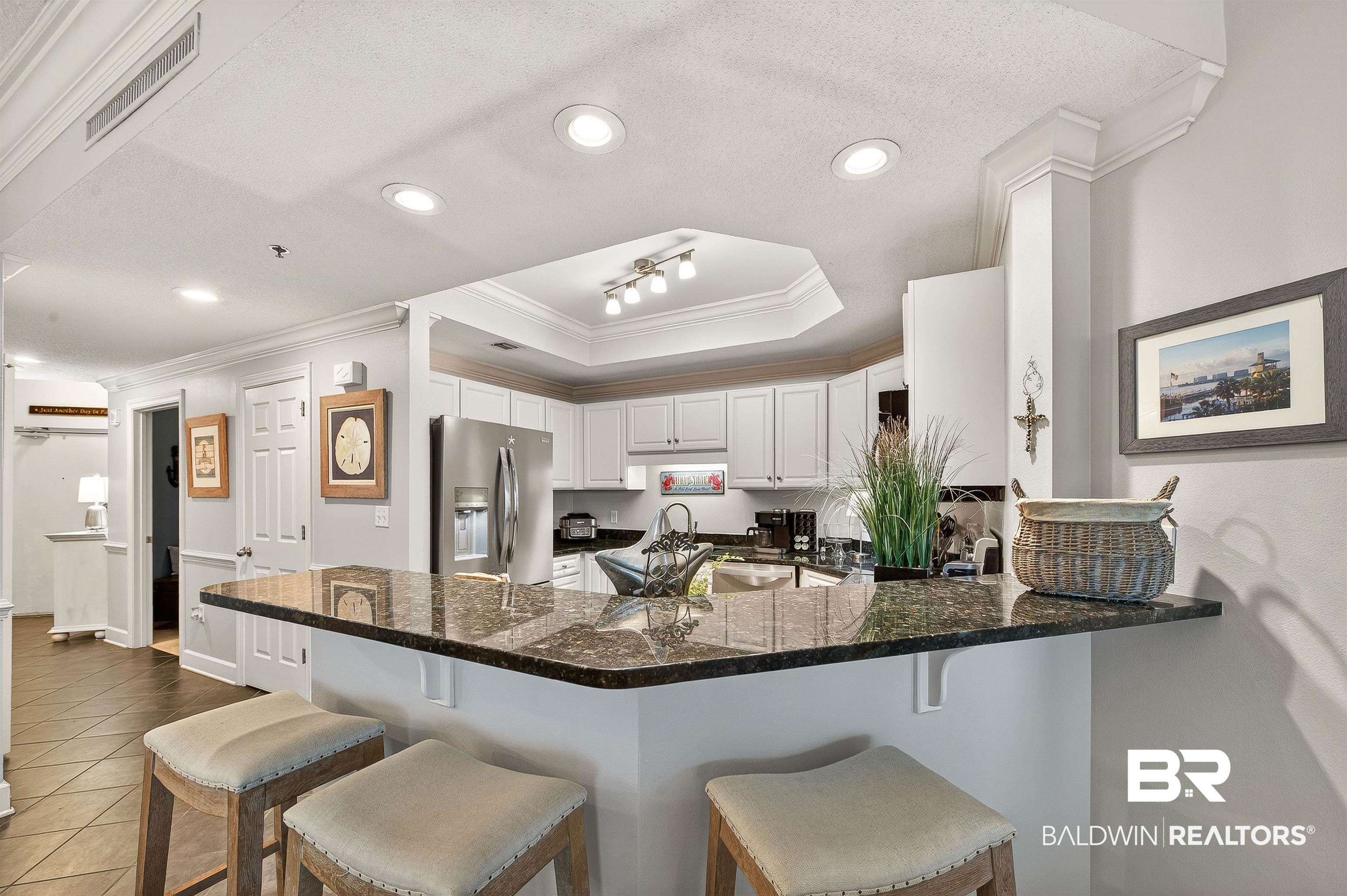 27582 Canal Road, Unit 2507 Orange Beach, AL 36561 - Photo 25 of 75 Kitchen with ornamental molding, white cabinetry, a kitchen breakfast bar, stainless steel fridge with ice dispenser, and dark stone counters