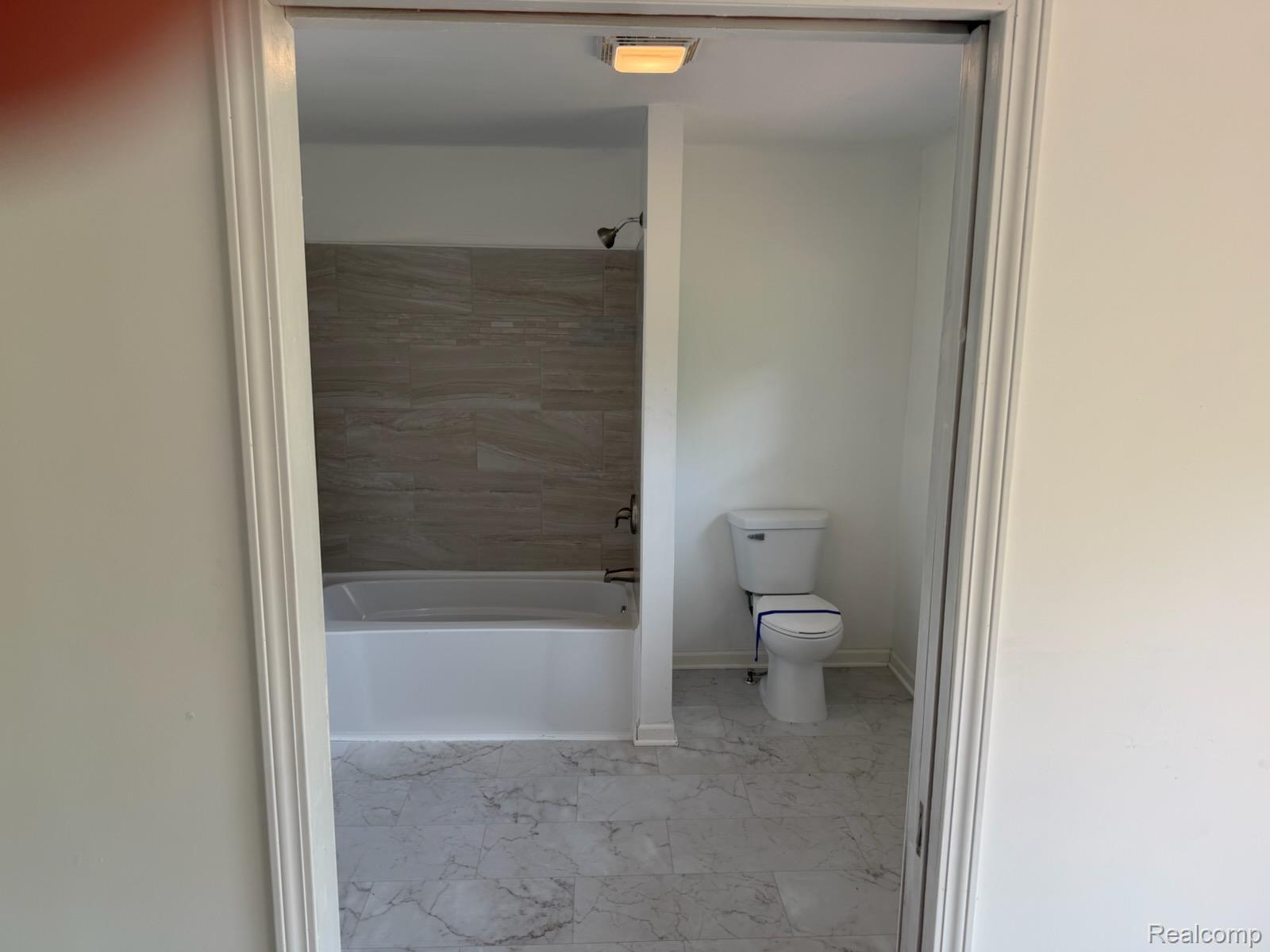 3515 Morton Road Stockbridge, MI 49285 - Photo 14 of 31 Bathroom with large format tile flooring, white bathtub, gray tile shower surround, and a white toilet