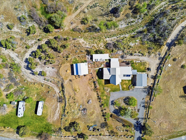 811 East Canyon Road Mayfield, UT 84643 - Photo 6 of 57 Aerial perspective showcasing a sprawling property featuring a main residence with a light-colored roof, multiple outbuildings, extensive natural landscaping, a paved driveway, and a circular turnaround area