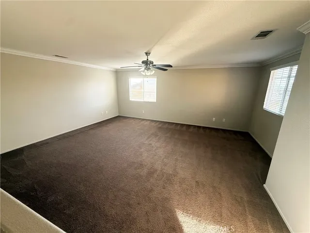 an empty room with windows and ceiling fan