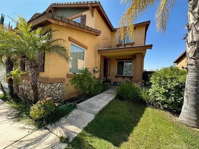 a view of a house with a small yard plants and large tree