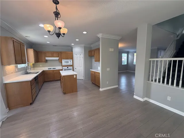 a open kitchen with stainless steel appliances granite countertop a refrigerator a sink dishwasher a stove and a dining table with wooden floor