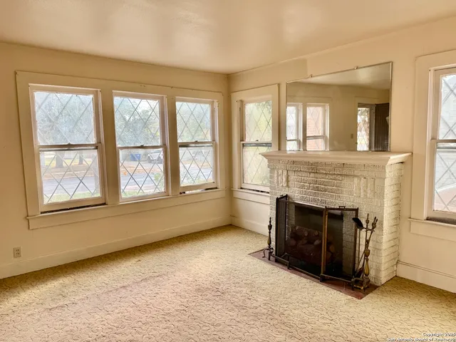 a view of an empty room with windows and a fireplace