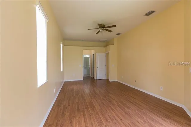 a view of a hallway with wooden floor and a ceiling fan