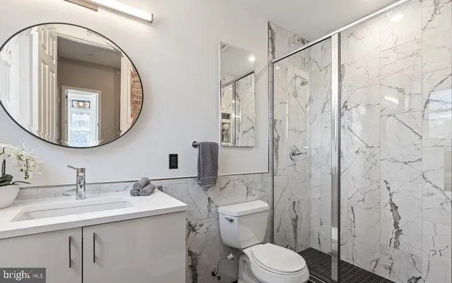 a bathroom with a toilet a sink a mirror a vanity and shower