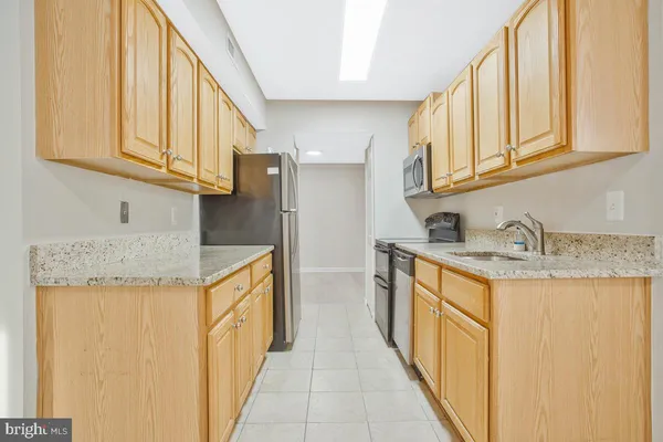 a kitchen with stainless steel appliances granite countertop a sink and a refrigerator