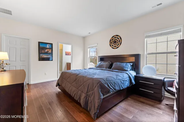 a bedroom with a bed and a dresser with wooden floor