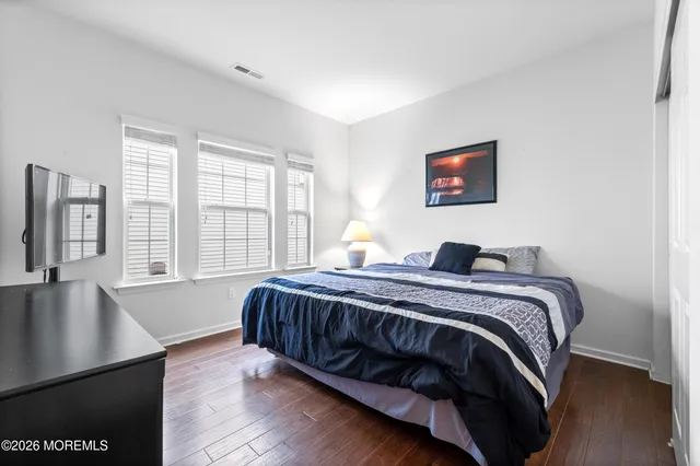 a spacious bedroom with a bed and wooden floor