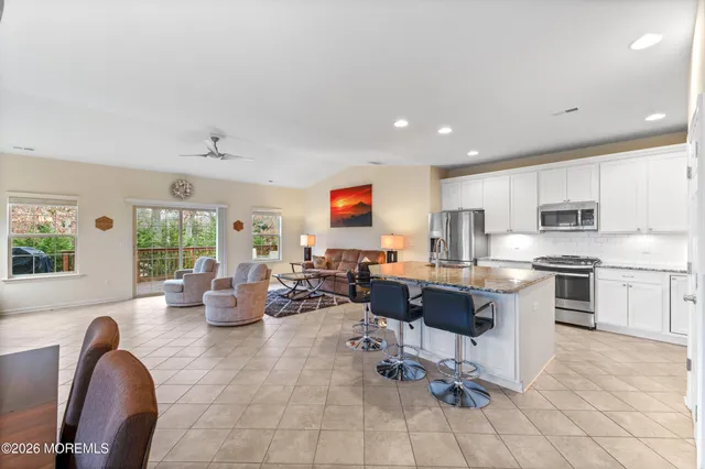a large white kitchen with stainless steel appliances lots of white furniture a window and a sink