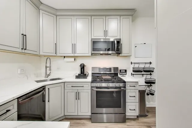 a kitchen with stainless steel appliances granite countertop a stove a sink and a microwave