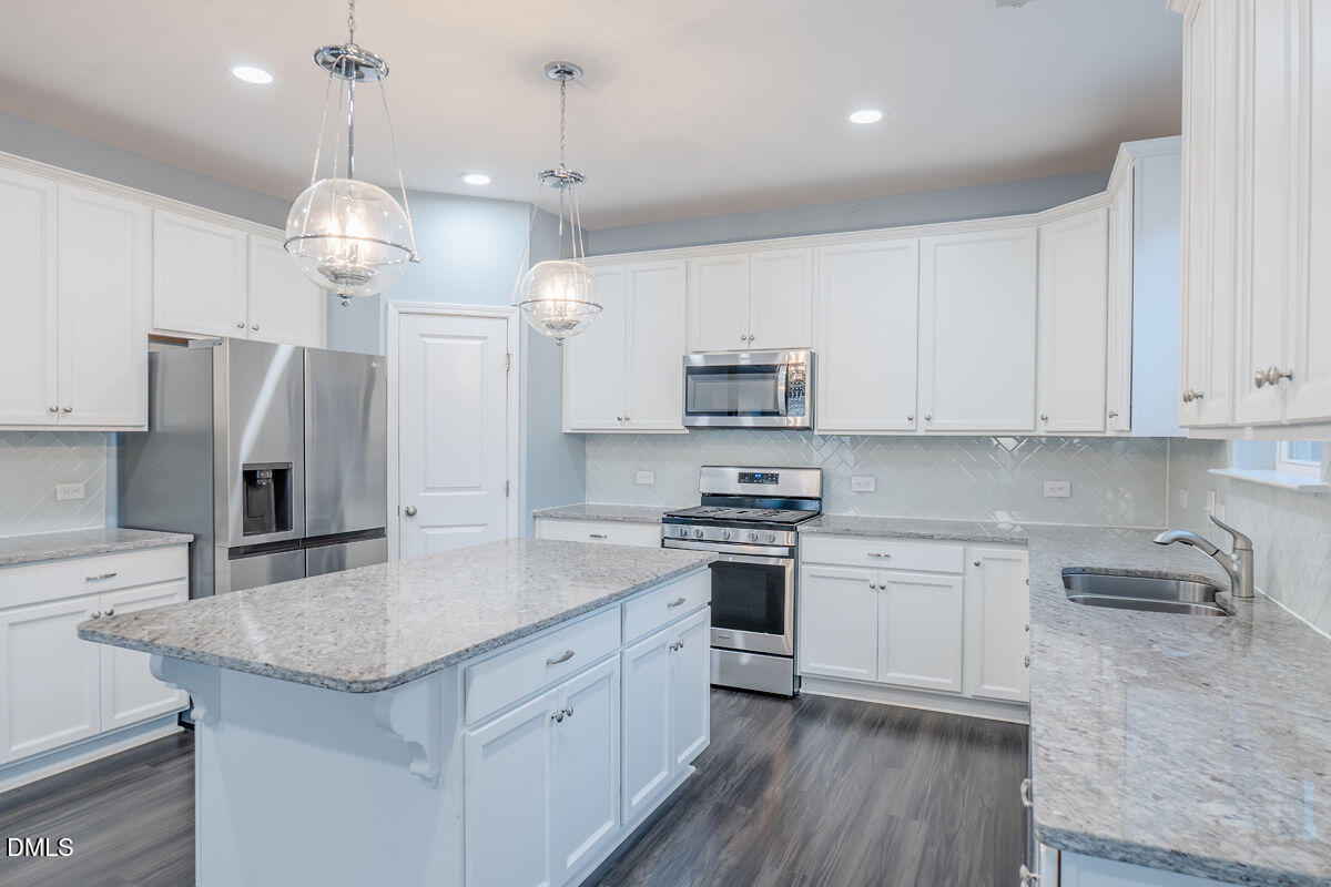 87 East Ravano Drive Clayton, NC 27527 - Photo 14 of 37 a kitchen with stainless steel appliances granite countertop a sink a stove a refrigerator a center island and cabinets