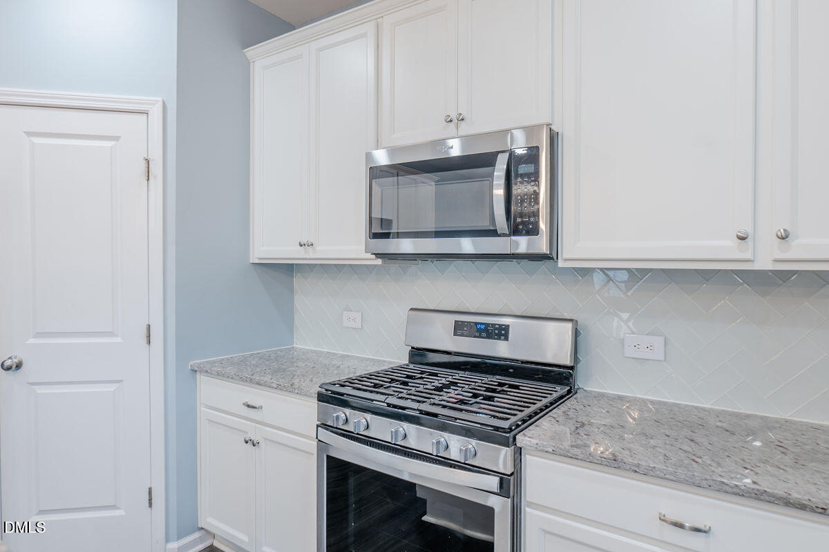 87 East Ravano Drive Clayton, NC 27527 - Photo 15 of 37 a kitchen with stainless steel appliances granite countertop white cabinets and a stove top oven