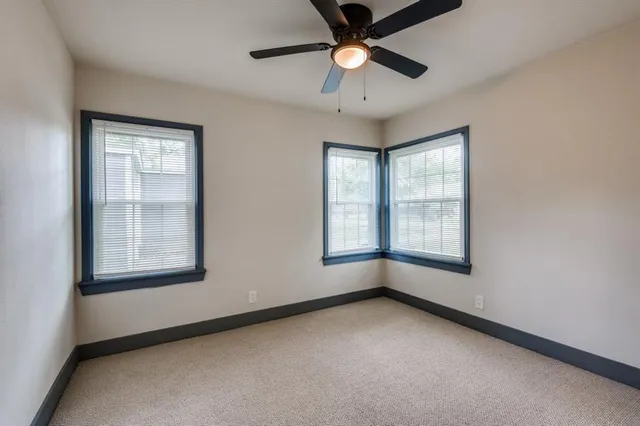 an empty room with chandelier fan and windows