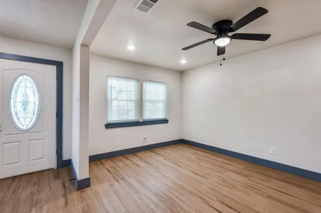 an empty room with wooden floor fan and windows