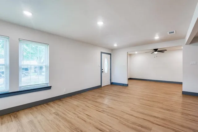 an empty room with wooden floor and windows