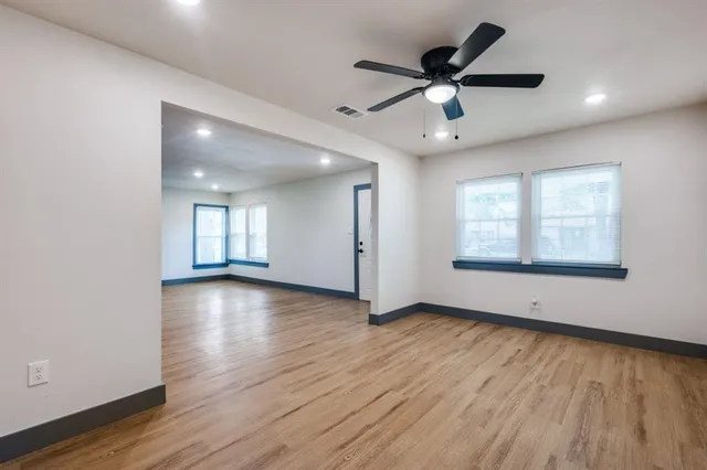 a view of an empty room with wooden floor and a window