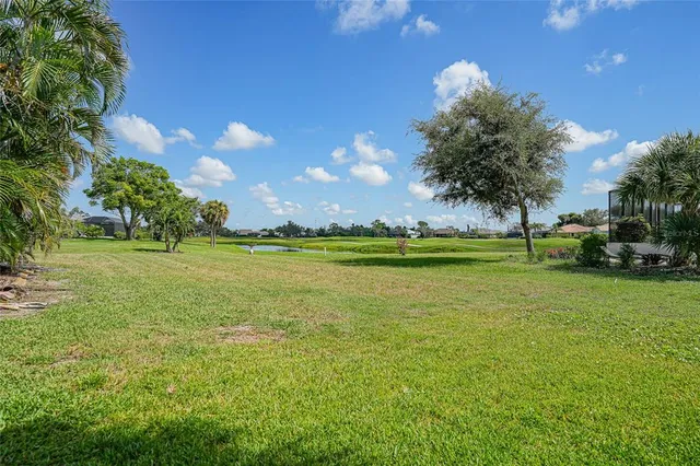 a view of a house with a yard and palm trees
