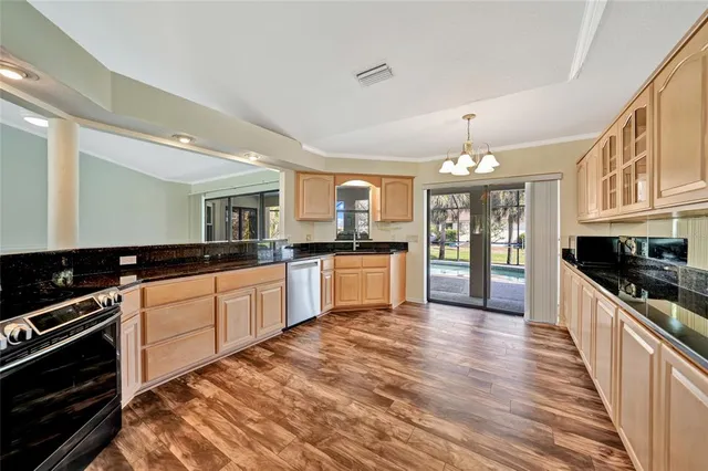 a large kitchen with granite countertop a stove top oven a sink dishwasher a dining table and chairs with wooden floor