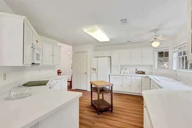 a kitchen with white cabinets and chairs