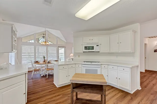 a kitchen with stainless steel appliances a stove a sink dishwasher and white cabinets with wooden floor