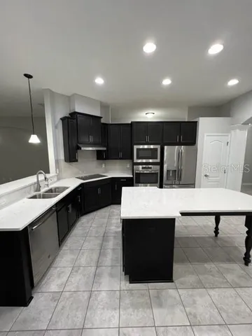 a large living room with stainless steel appliances kitchen island a sink dishwasher a living room with couches and floor to living room