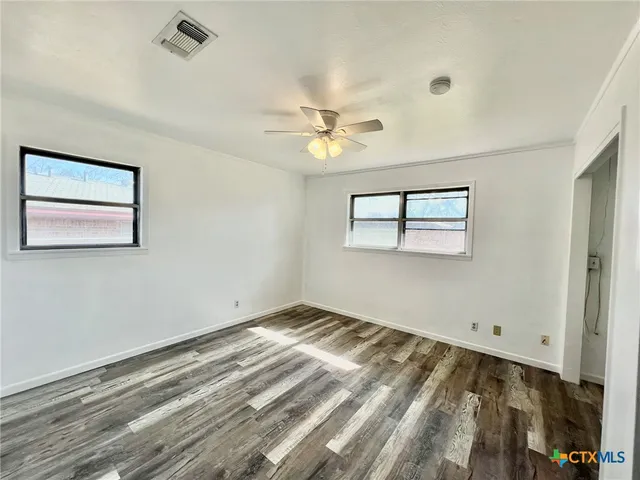 a view of a room with wooden floor and a ceiling fan