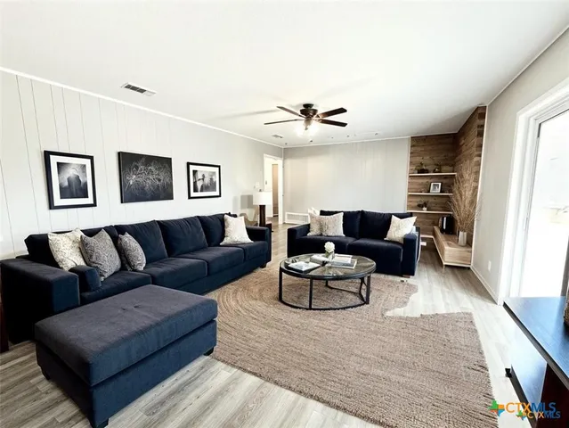 a living room with furniture a ceiling fan and a wooden floor