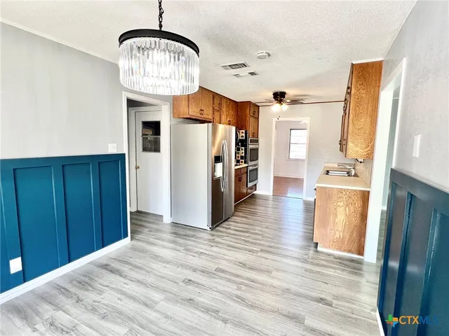 a view of a kitchen with refrigerator and wooden floor