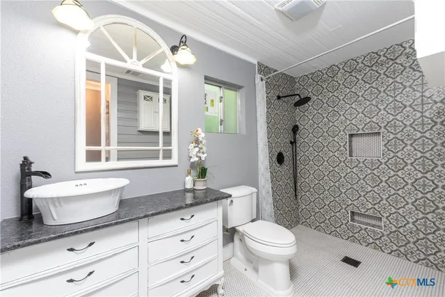 a bathroom with a granite countertop toilet sink and mirror