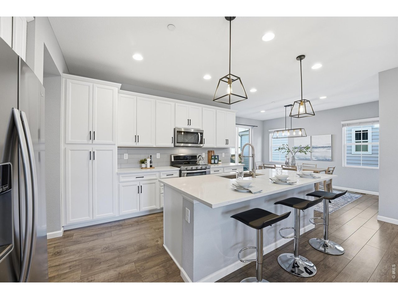 10094 Flower Street Broomfield, CO 80021 - Photo 9 of 40 a open kitchen view with stainless steel appliances granite countertop a sink dishwasher a refrigerator a stove a dining table and chairs with wooden floor