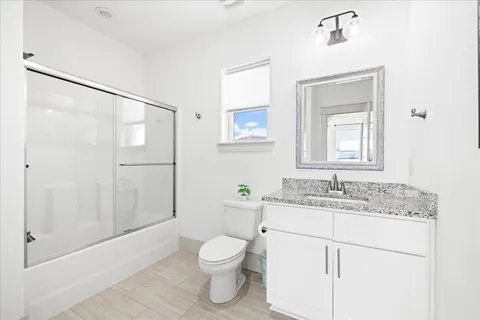 a bathroom with a granite countertop sink toilet and shower