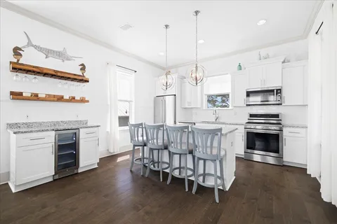 a kitchen with stainless steel appliances a stove a sink dishwasher a refrigerator white cabinets and wooden floor