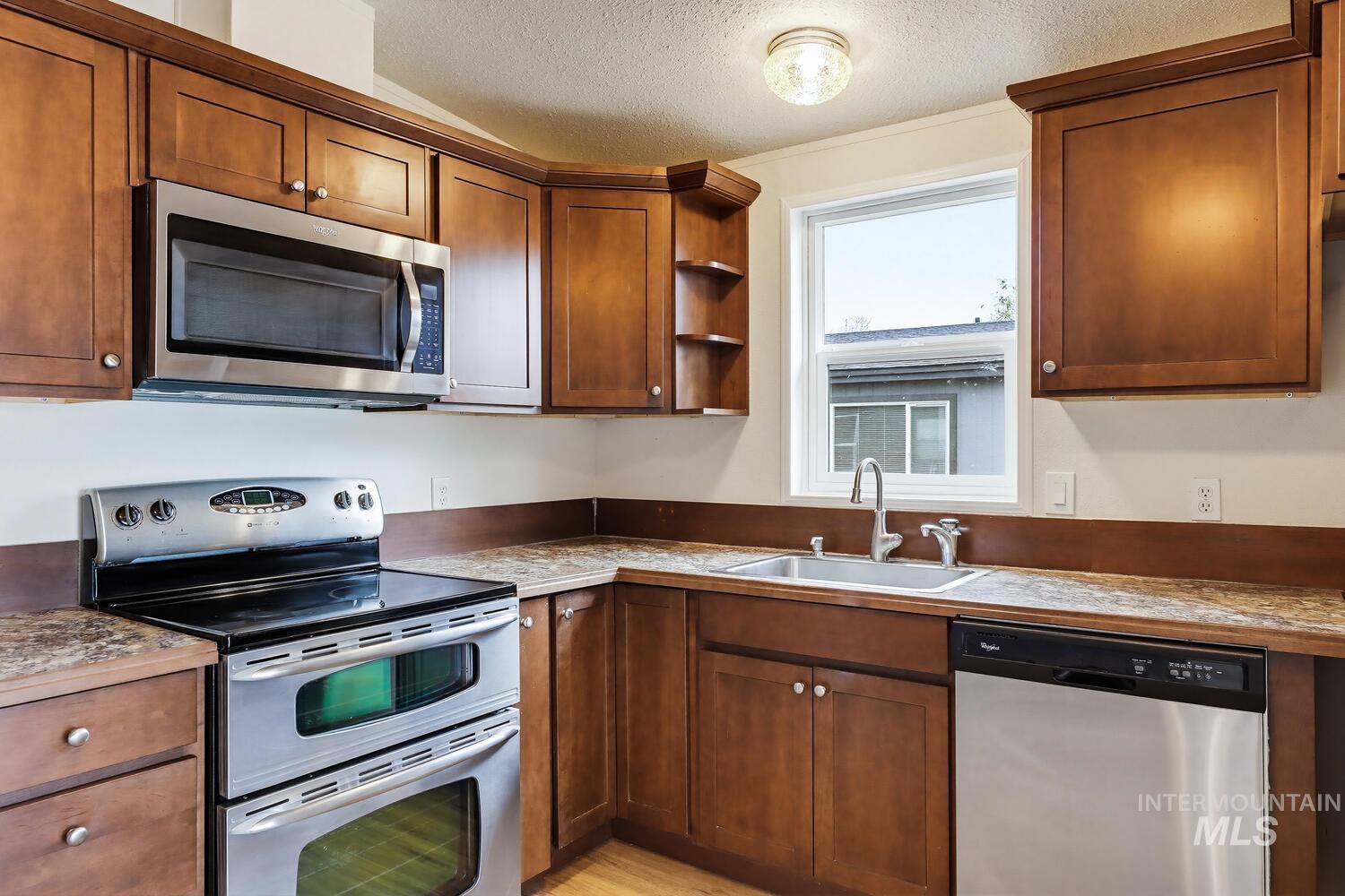 162 1st Street North Marsing, ID 83639 - Photo 11 of 39 Kitchen with stainless steel appliances, a textured ceiling, open shelves, and wood finish cabinets