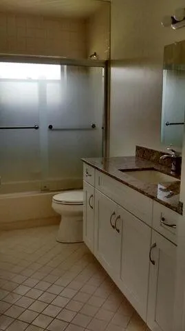 a bathroom with a granite countertop sink a toilet and a mirror