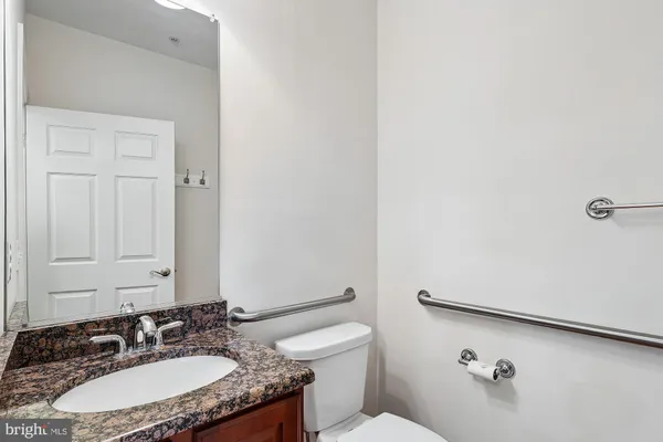 a bathroom with a granite countertop sink a toilet and a mirror