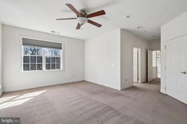 an empty room with a ceiling fan and windows