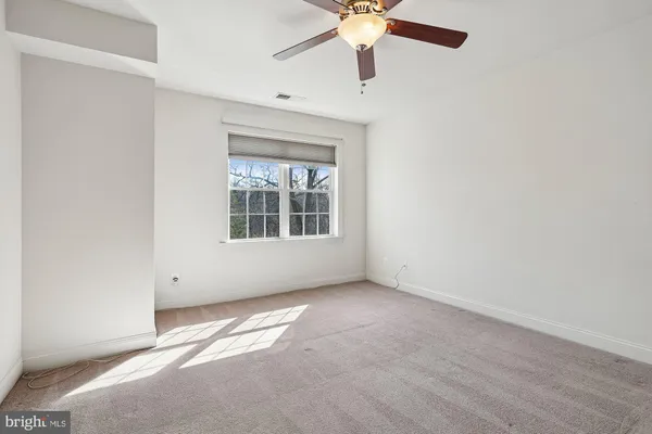an empty room with a window and a fan