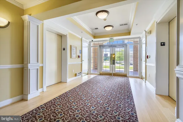 a view of a hallway with wooden floor and a bathroom