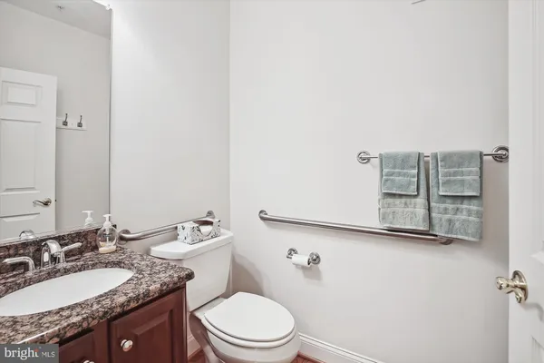 a bathroom with a granite countertop sink mirror vanity and toilet