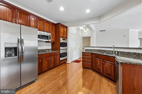 a kitchen with stainless steel appliances granite countertop a refrigerator a sink and a stove