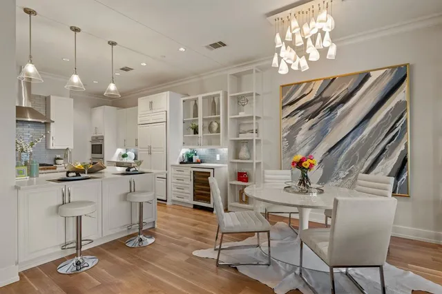 a kitchen with stainless steel appliances kitchen island granite countertop a table chairs in it and wooden floors