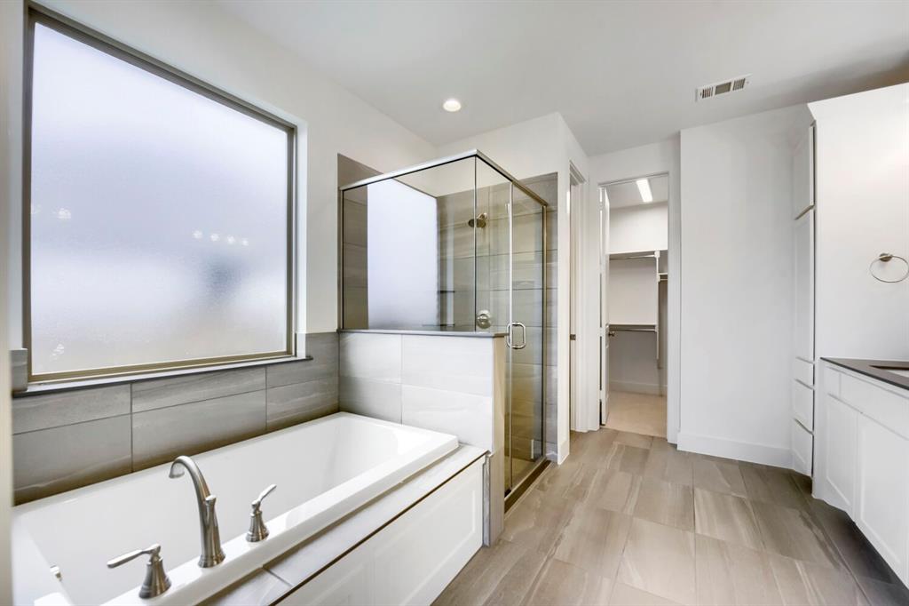 11548 Wulstone Road Haslet, TX 76052 - Photo 14 of 26 Contemporary bathroom featuring a built-in tub with brushed nickel fixtures, a glass-enclosed shower, and a large frosted window