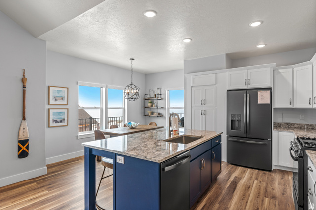 1343 North Trapper Loop Garden City, UT 84028 - Photo 40 of 56 Kitchen featuring stainless steel appliances, two tone cabinets, light stone countertops, light wood-type flooring, and hanging lights