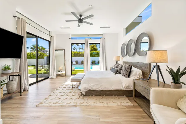 a bedroom with a large bed a flat screen tv and windows