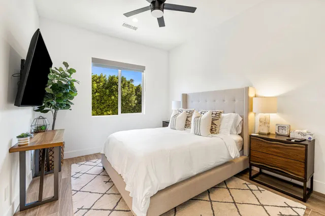 a bedroom with a bed and a flat tv screen on dresser
