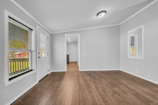 a view of an empty room with wooden floor and windows