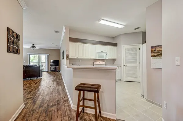 a living room with stainless steel appliances furniture a refrigerator and kitchen view