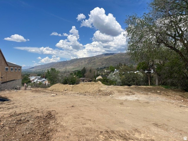 795 Abby Lane, Unit 5 Bountiful, UT 84010 - Photo 1 of 9 Expansive undeveloped lot featuring clear land, a partial brick structure, mountain backdrop, and scattered mature trees